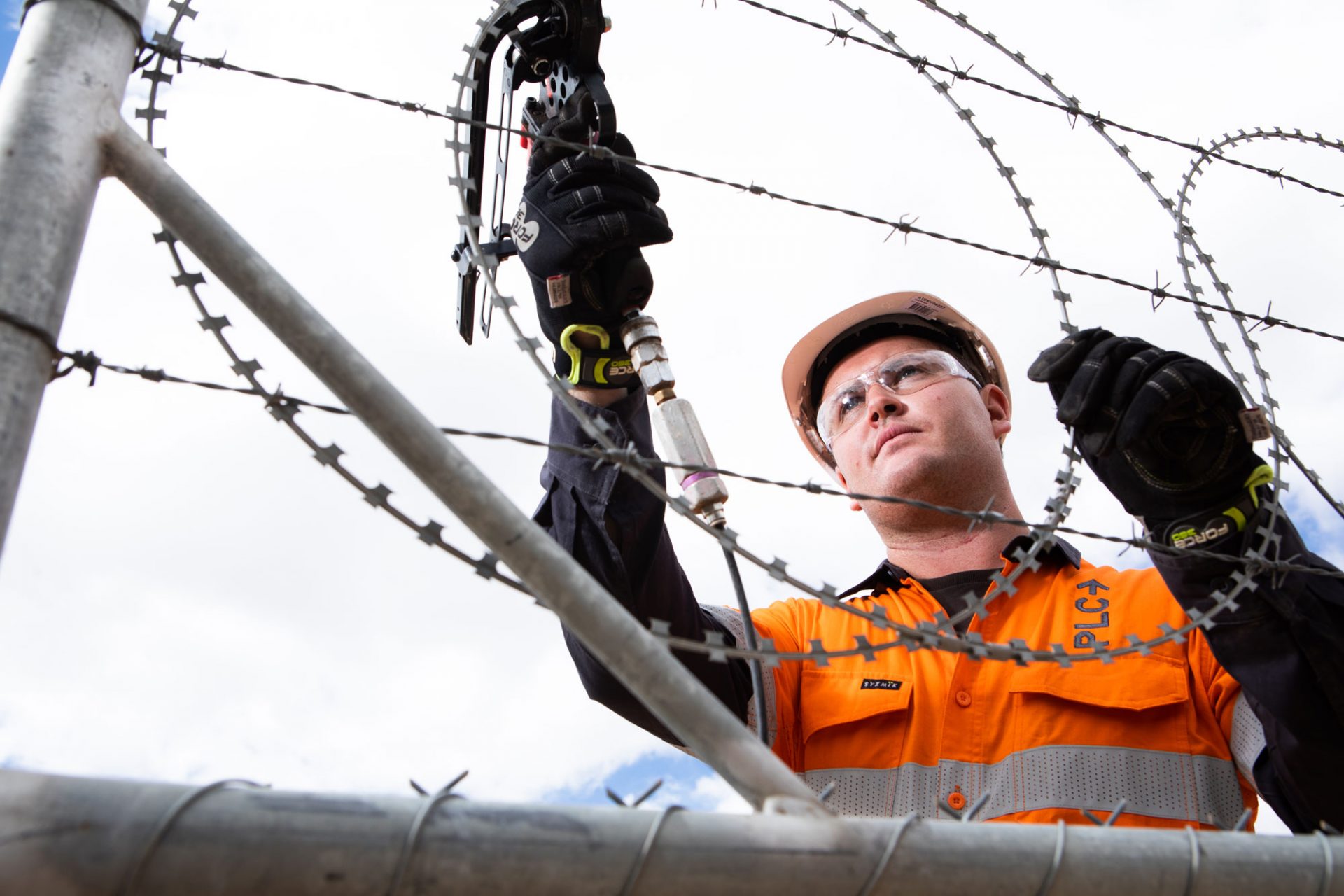 PLC worker installs security razor wire.